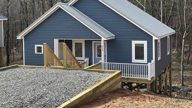 Une maison à deux étages avec une terrasse, une porte d’entrée et une boîte aux lettres.