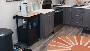 Une cuisine moderne avec des meubles gris, un four à micro-ondes, une machine à café et un bol pour chien.