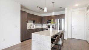 Una cocina moderna con gabinetes de madera oscura, electrodomésticos de acero inoxidable y una isla central con taburetes de bar.