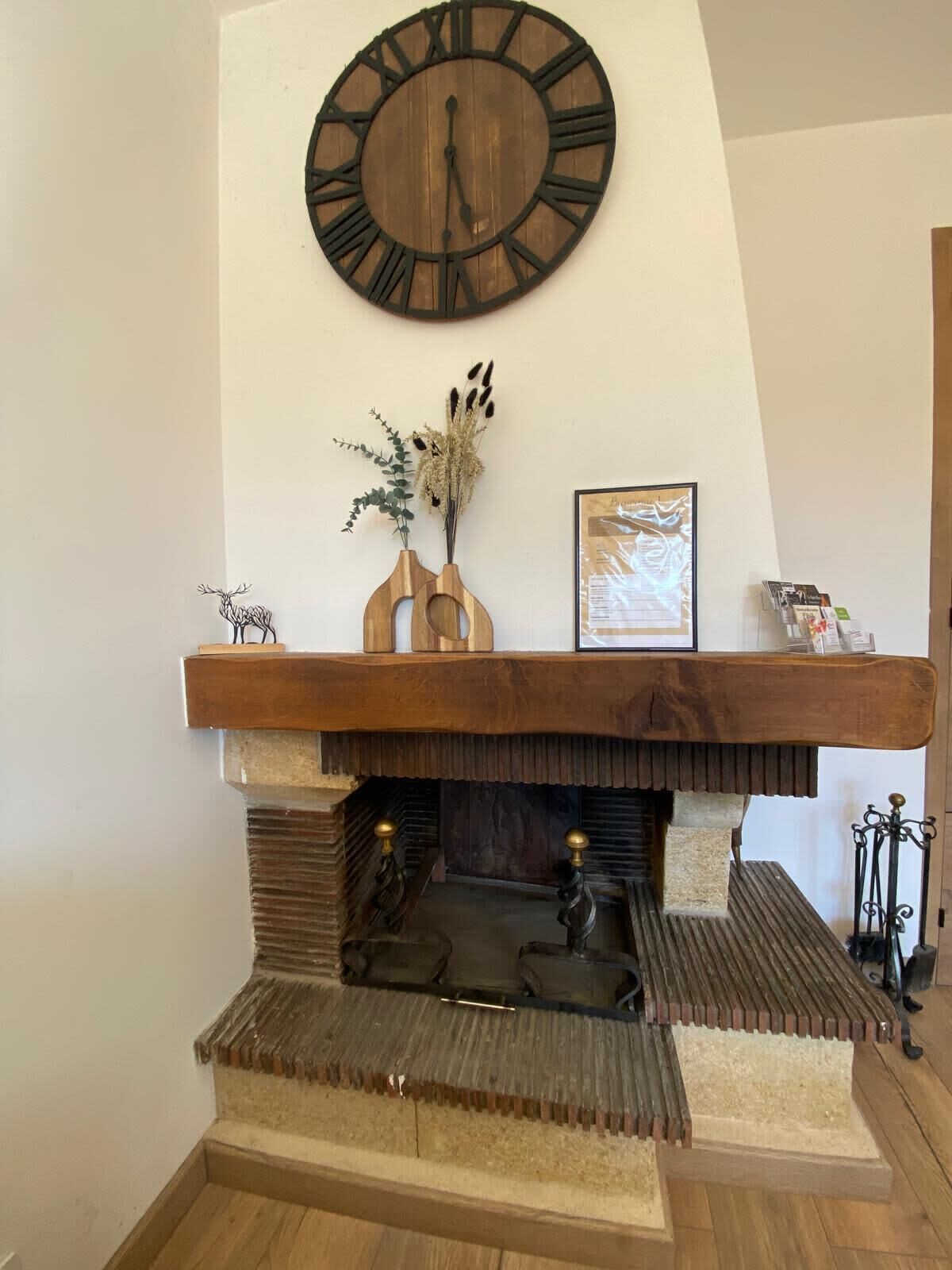 A fireplace with a wooden mantel, a large wall clock, and a framed picture.
