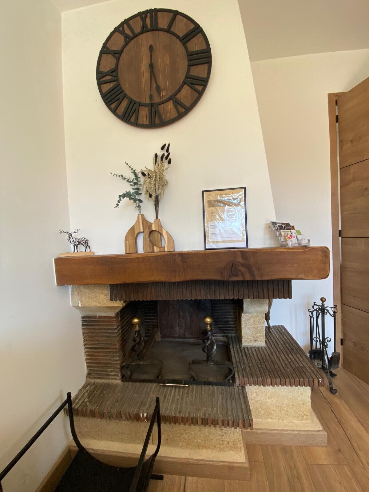 A fireplace with a wooden mantel, a clock above it, and a framed picture on the mantel.
