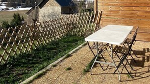 Eine Terrasse mit Tisch und Stühlen, ein Holzzaun und ein Blick auf eine verschneite Berglandschaft.