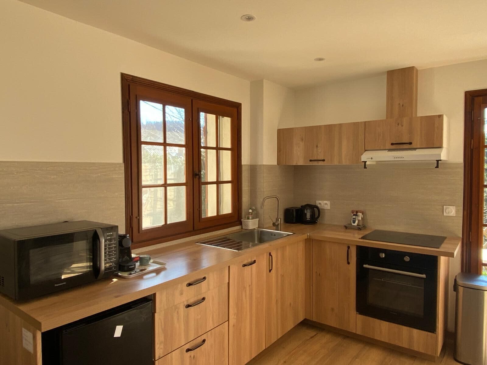 Una cocina compacta con armarios de madera, un microondas, un lavavajillas y una estufa.