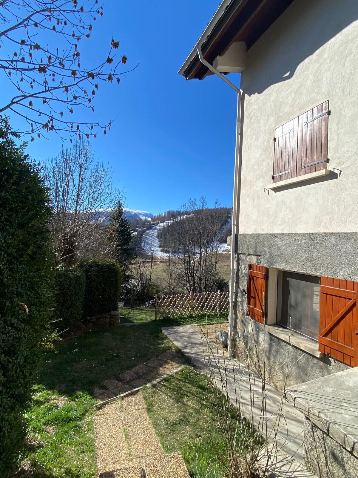 A house with a stone exterior, a wooden fence, and a clear view of a mountain range.