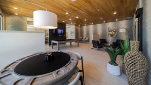 Ein modernes Wohnzimmer mit Pooltisch, Sitzgruppe und Fernseher.