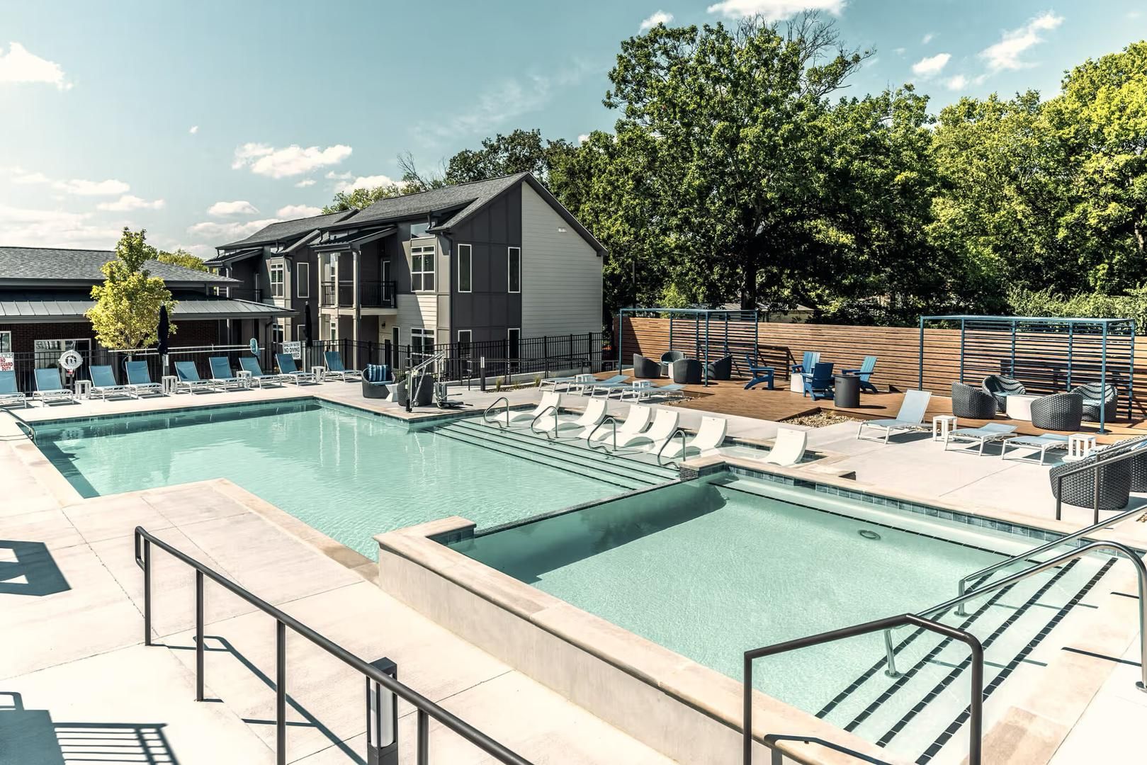 A swimming pool with lounge chairs and a building with a balcony.