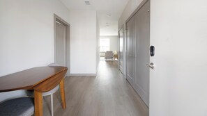 A hallway with a wooden table, a grey door with a keyhole, and a chair. - Landing | Modern 1BD, Clubhouse, Pool (Nashville)