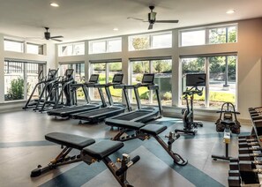 Ein Fitnessraum mit Laufbändern, Rudergeräten und Gewichtsbänken.