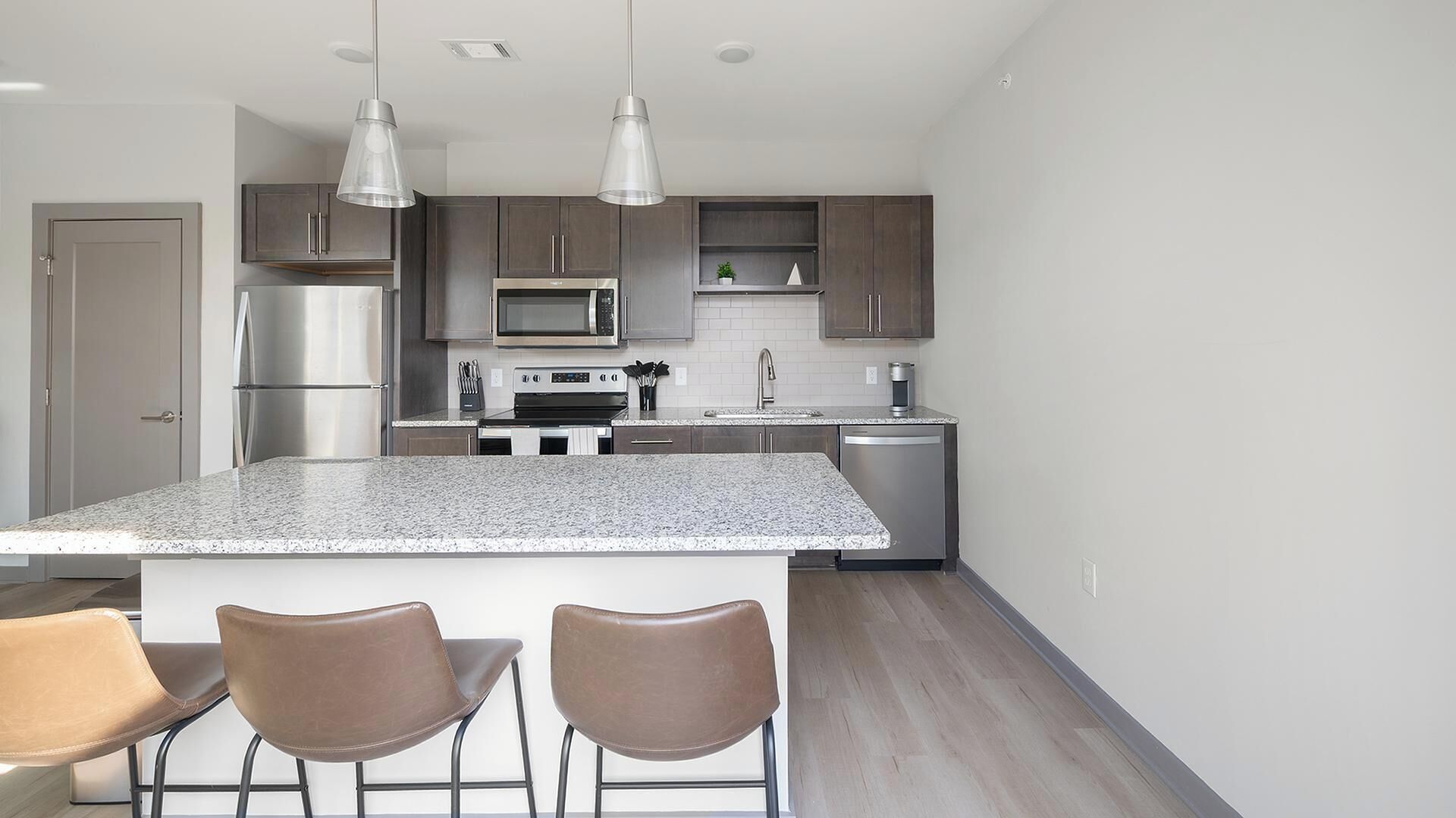 A modern kitchen with a central island, stainless steel appliances, and pendant lighting.