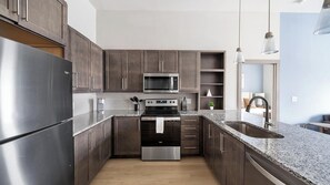 Eine moderne Küche mit dunklen Holzschränken, Edelstahlgeräten und einer Granitarbeitsplatte.