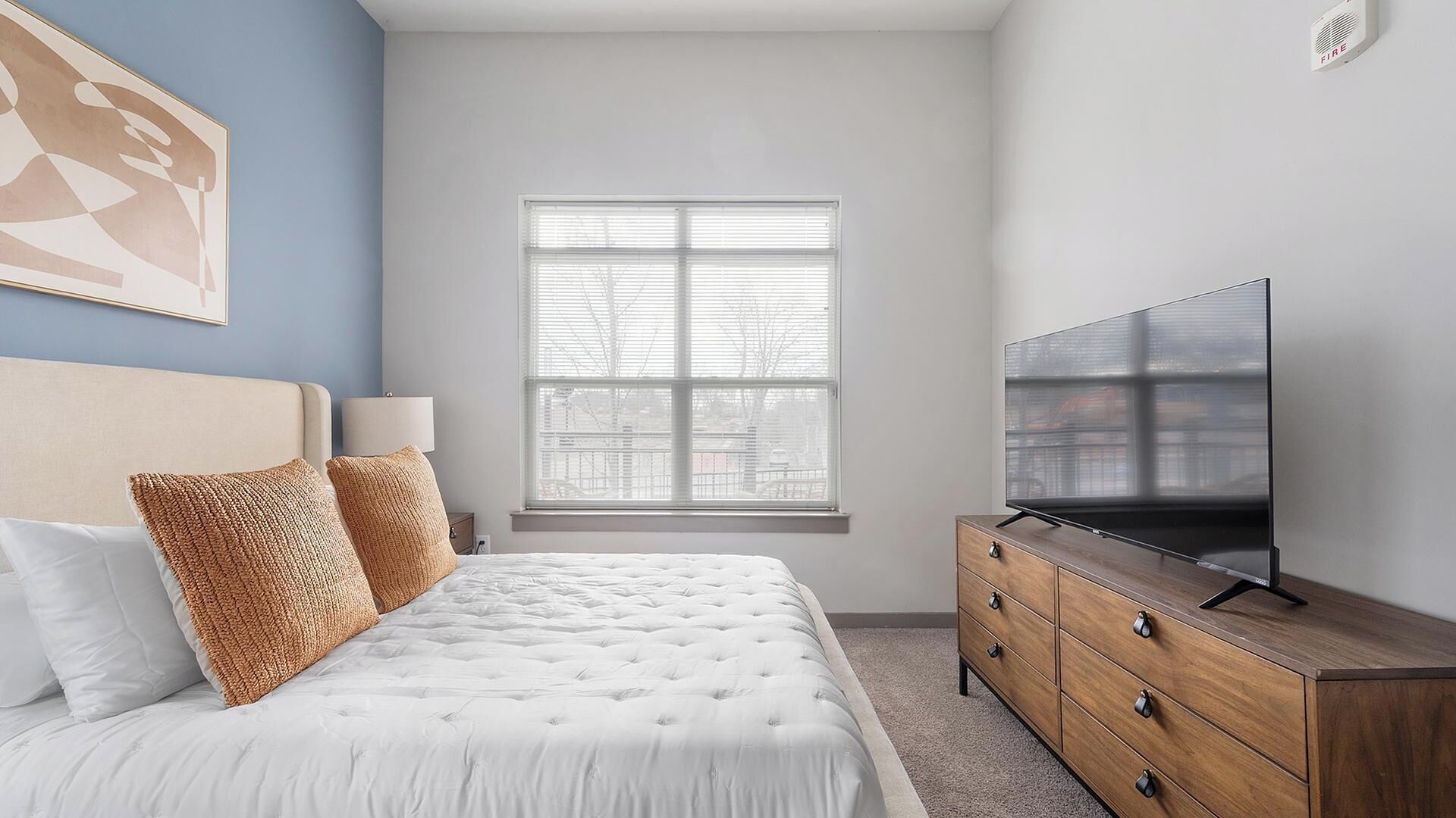 Une chambre à coucher avec un lit, une télévision, une commode et une fenêtre.