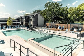Ein Schwimmbecken mit Liegestühlen und ein Gebäude mit einem Balkon.