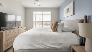 Une chambre d’hôtel avec un lit, une télévision, une table de chevet et une fenêtre avec des stores.