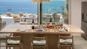 Un coin repas avec une table dressée pour quatre personnes, offrant une vue imprenable sur l’océan.