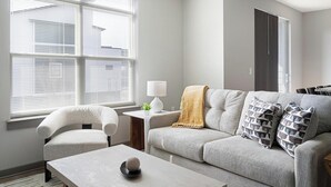 Una sala de estar con sofá, sillón, mesa de centro y lámpara.
