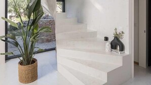 A modern interior with a staircase, a potted plant, and a vase on a shelf. - Villa Gelos by Villas Hvar (Zavala)