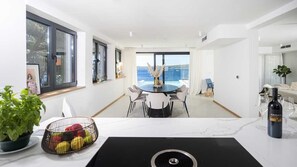 Una cocina moderna con comedor, ventanas amplias y vistas al mar.