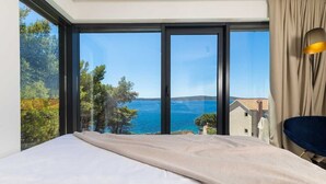 A bedroom with a large window, a bed, and a view of the sea. - Villa Gelos by Villas Hvar (Zavala)