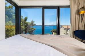 Ein Schlafzimmer mit großem Fenster, einem Bett und Meerblick.