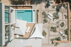 Ein Luftbild eines Poolbereichs auf einem Dach mit einem klaren, blauen Pool, weißen Sonnenschirmen und Liegestühlen.