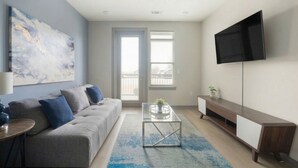 Una sala de estar con sofá, mesa de centro, televisor y obras de arte.