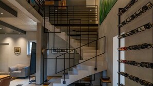 Un intérieur moderne agrémenté d’un escalier, de verres à vin fixés au mur et de guitares encadrées.
