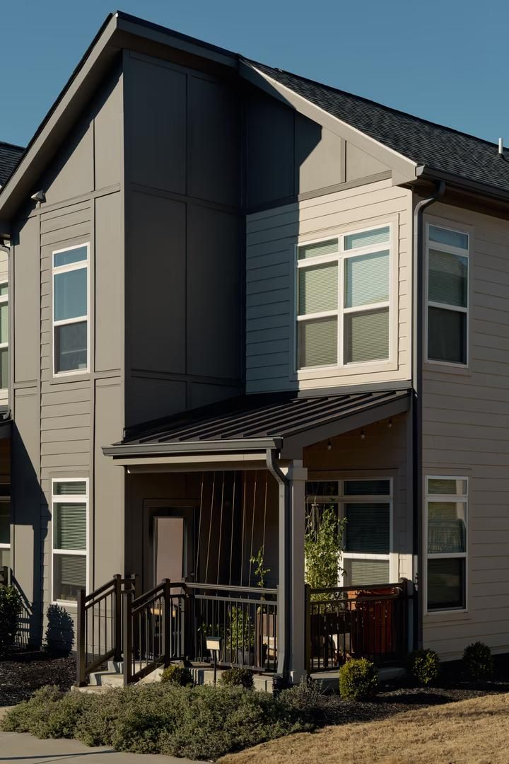 A two-story residential building with a covered front porch and a small front yard.