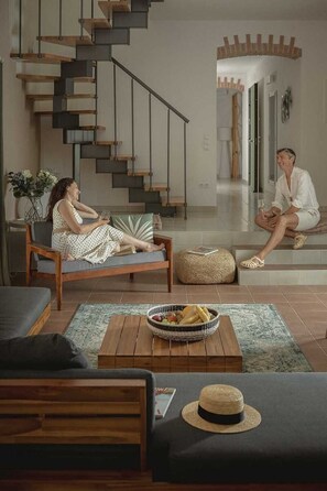 A modern living room with a staircase, a sofa, a coffee table with a basket, and a hat on the floor. - Villa Lesina by Villas Hvar (Vrboska)