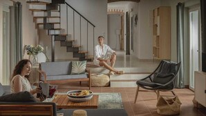 A modern living room with a sofa, a coffee table, a chair, and a staircase. - Villa Lesina by Villas Hvar (Vrboska)
