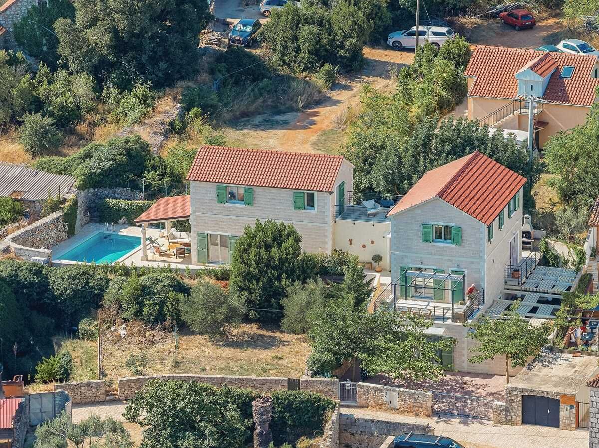 Une maison à deux étages avec une piscine, entourée d’arbres et d’autres maisons.