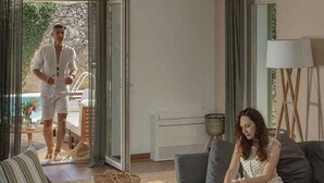 A living room with a sofa, a chair, a coffee table with fruit, and a person sitting. - Villa Lesina by Villas Hvar (Vrboska)
