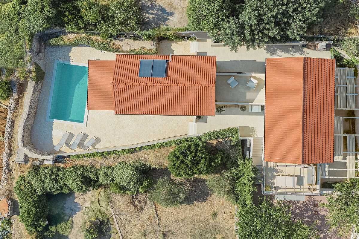 A two-story house with a swimming pool, a covered patio, and a large garden.