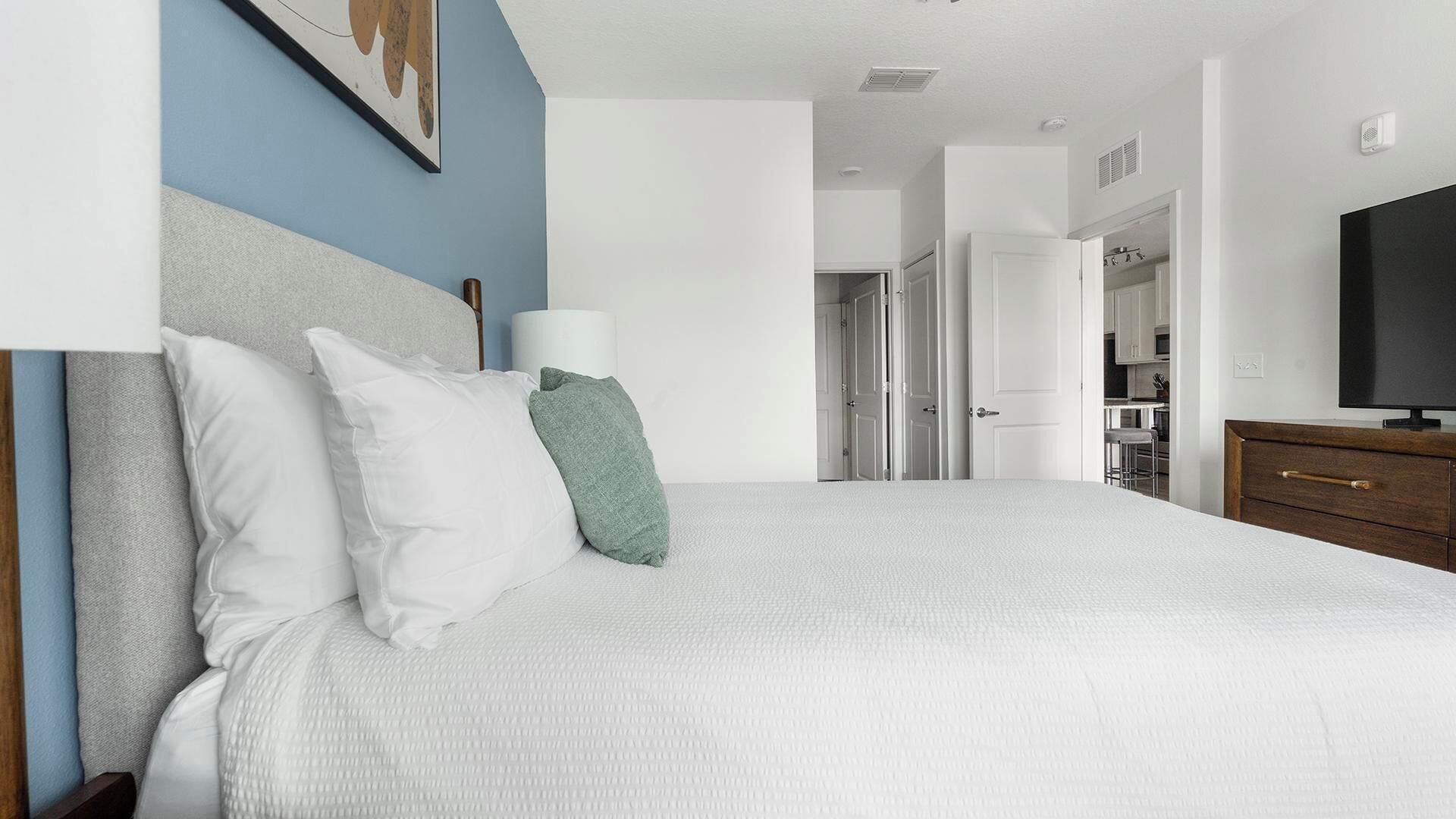 A bedroom with a bed, a bedside lamp, a television, and a wardrobe.