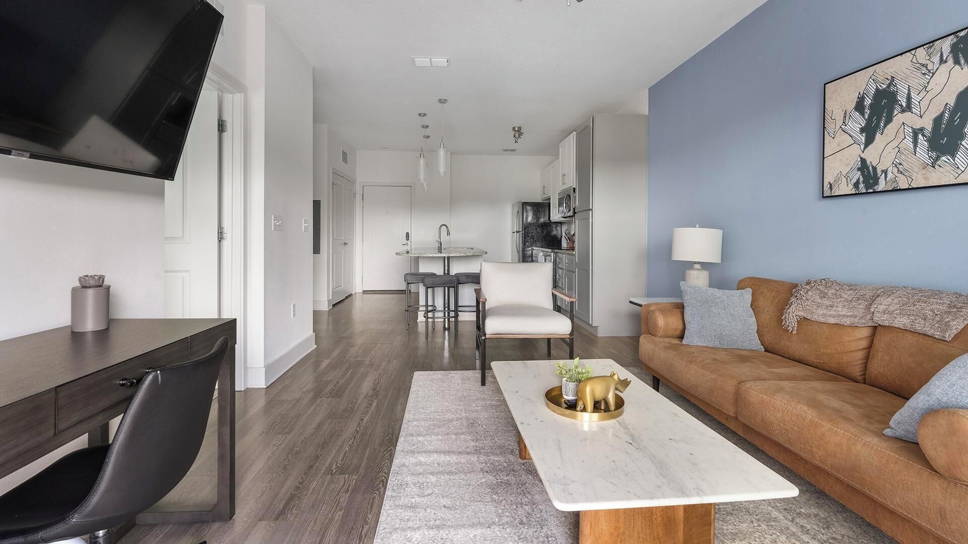 A modern living room with a flat-screen TV, a sofa, a coffee table, and a dining area with chairs.