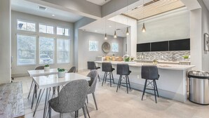 A modern kitchen with a central island, bar stools, and a dining table with chairs. - Landing | Amazing 1BD, Clubhouse, Pool (Venice)