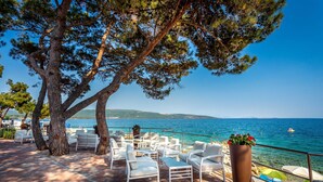 An outdoor seating area with white chairs and tables, overlooking a body of water.