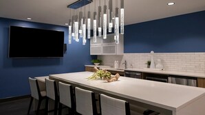 Una cocina moderna con una isla grande, armarios blancos e iluminación colgante.