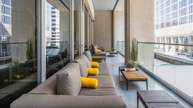 Un salón moderno con un sofá largo, mesitas pequeñas y plantas en macetas.
