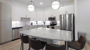 Una cocina moderna con encimeras de granito, electrodomésticos de acero inoxidable e iluminación colgante.