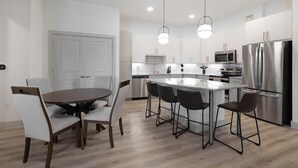 Una cocina moderna con una isla central, electrodomésticos de acero inoxidable y un comedor con una mesa redonda y sillas.