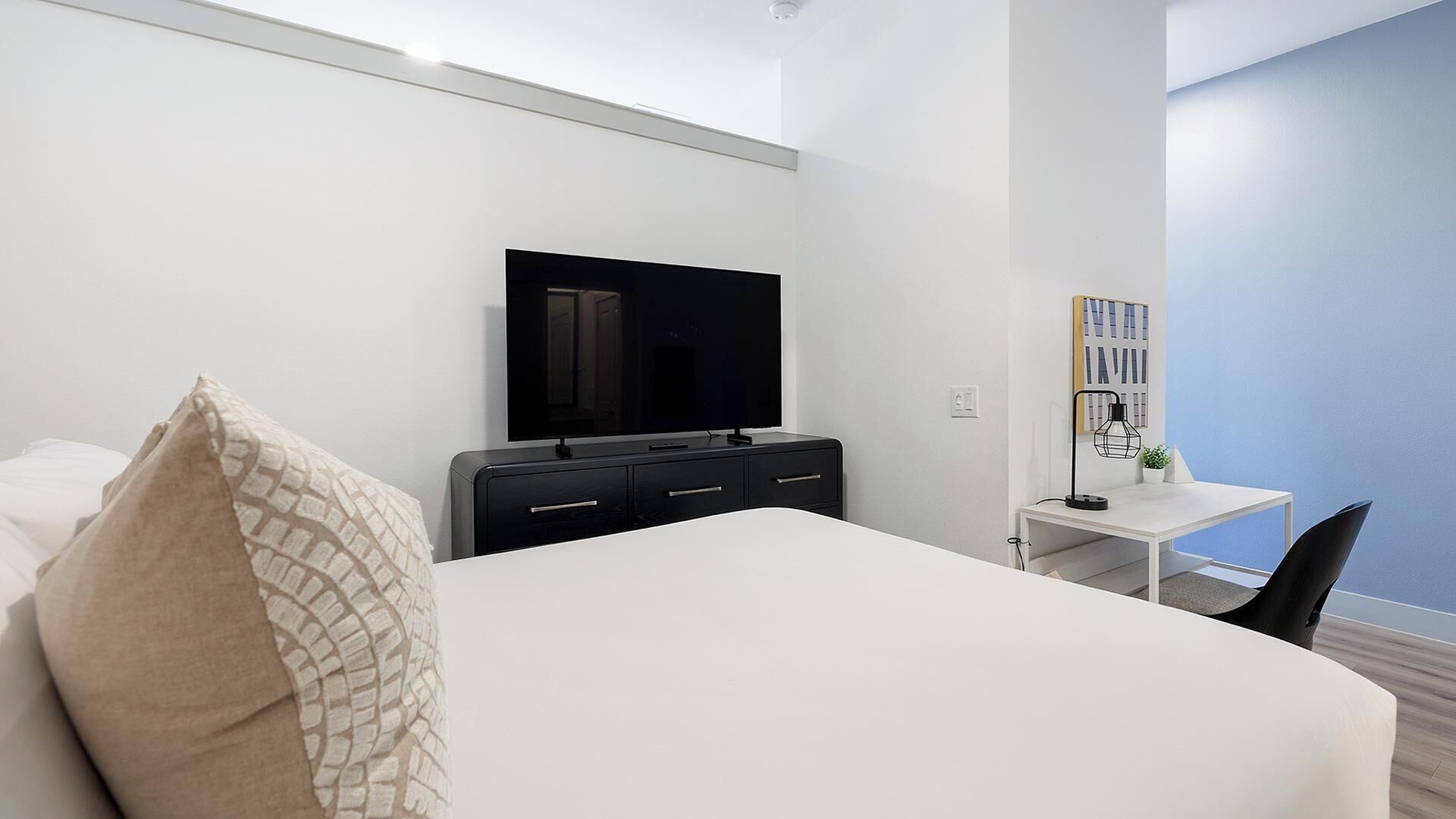 Une chambre d’hôtel avec un lit, une télévision, un bureau et une chaise.