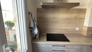 A compact kitchen with a window, a built-in stove, and a countertop. - Apartment Perpignan center 92 m2, 2 bedrooms 2 bathrooms, parking (Perpignan)