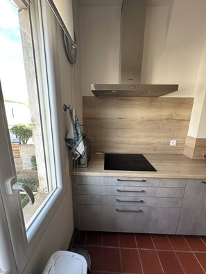 A compact kitchen with a window, a built-in stove, and a countertop. - Apartment Perpignan center 92 m2, 2 bedrooms 2 bathrooms, parking (Perpignan)