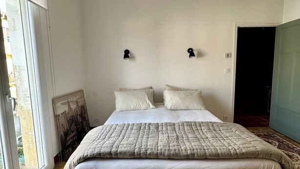 A bedroom with a large bed, a window, and a door. - Apartment Perpignan center 92 m2, 2 bedrooms 2 bathrooms, parking (Perpignan)