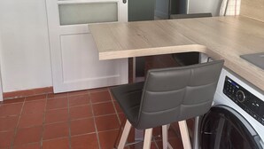 A compact kitchen with a wooden countertop, a washing machine, and a chair. - Apartment Perpignan center 92 m2, 2 bedrooms 2 bathrooms, parking (Perpignan)