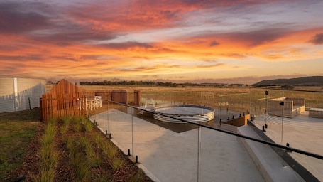 A modern outdoor pool area with a wooden fence, a concrete deck, and a view of the landscape.. Piper's Grove - a luxury modern farmhouse retreat near Lake George