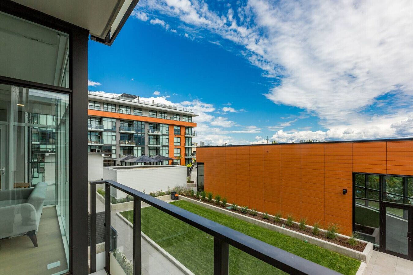 A modern building with large windows, a balcony, and a clear sky.