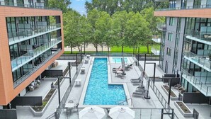 Un edificio moderno con piscina central, zona de estar al aire libre y vistas despejadas de la vegetación circundante.