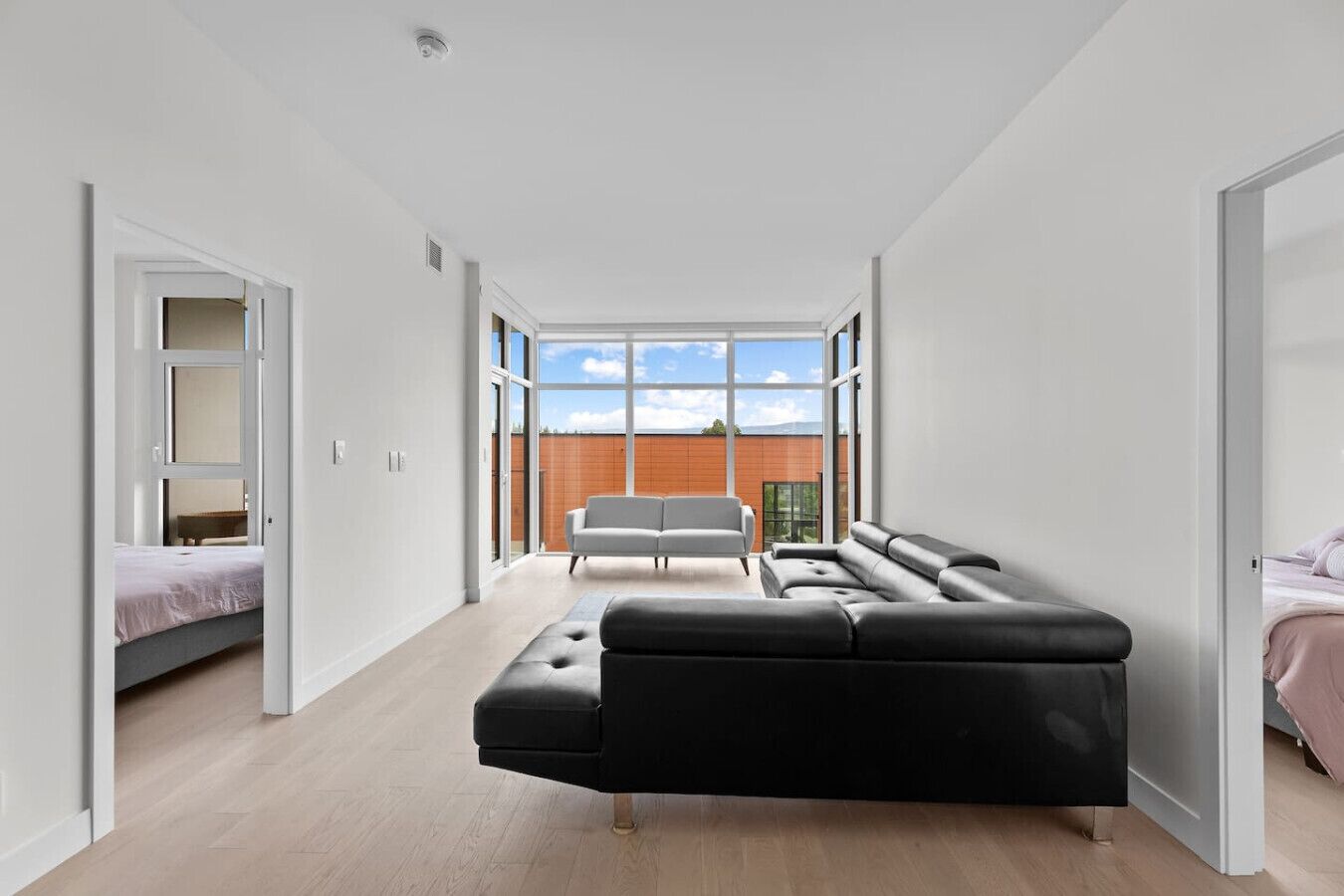 A modern bedroom with a large window, a sofa, and a bed.