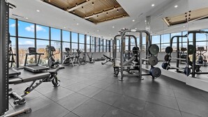 Un gimnasio moderno con diverso equipo de ejercicio, amplias ventanas y techo alto.